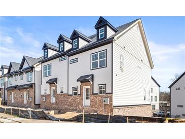 Beautiful new construction townhomes featuring white siding, brick accents, and black trim under a clear blue sky at 1991 Hollywood Nw Rd # 14, Atlanta, GA 30318