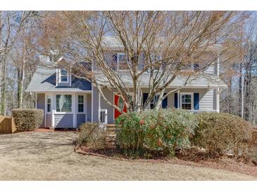 Charming two-story home with a well-maintained lawn, complemented by mature trees and a welcoming red front door at 2011 Two Springs Way, Lawrenceville, GA 30043