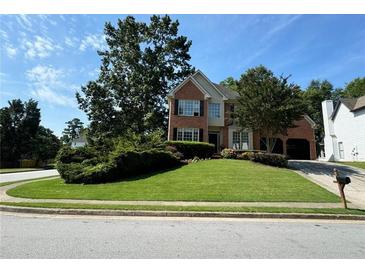 Charming two-story brick home with a lush, green front yard and mature trees at 1896 Lake Ridge Ter, Lawrenceville, GA 30043