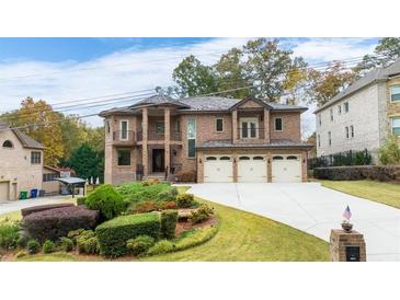 Elegant brick home featuring a three-car garage, manicured lawn, and a charming double-door entrance at 2146 Greensward Ne Dr, Atlanta, GA 30345