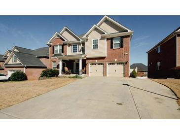 Charming two-story home featuring a brick and siding exterior, a spacious driveway, and a two-car garage at 980 Yancey Ct, Loganville, GA 30052