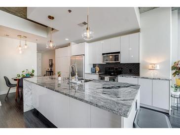 Modern kitchen features white cabinetry, stainless steel appliances, and a large island with a waterfall countertop at 44 Peachtree Nw Pl # 829, Atlanta, GA 30309