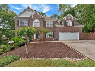 Charming two-story brick home features a well-manicured front yard, a two-car garage, and mature landscaping at 308 Lismore Ter, Woodstock, GA 30189