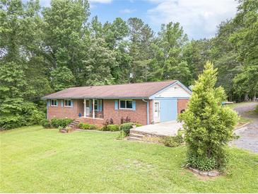 Charming brick home with a cozy front porch and blue shutters, surrounded by lush greenery and mature trees at 5255 Post Rd, Winston, GA 30187