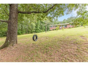 Lovely front yard features a mature tree and a tire swing at this brick home at 5255 Post Rd, Winston, GA 30187