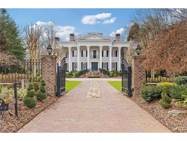 Grand estate featuring a gated entrance and impressive brick driveway leading to a columned facade and manicured landscaping at 3977 Sweet Bottom Dr, Duluth, GA 30096