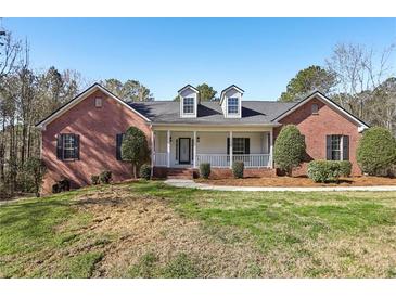 Charming brick home featuring a covered front porch, dormer windows, and a well-manicured lawn at 211 Garden W Walk, Hampton, GA 30228