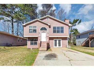 Charming split-level home with a pink exterior, front yard, and a driveway at 6404 Eastbriar Dr, Lithonia, GA 30058