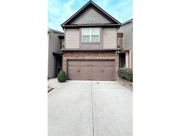 Two-story townhome featuring a two-car garage with brown doors and stone accents at 6642 Story Circle Cir, Norcross, GA 30093