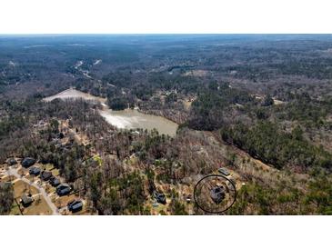 Aerial view of a wooded neighborhood with a pond nearby at 582 Black Forest Run, Douglasville, GA 30134