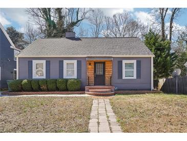 Charming single-story home featuring brick walkway, manicured hedges, gray siding and a cozy front porch at 1694 Kenmore Sw St, Atlanta, GA 30311