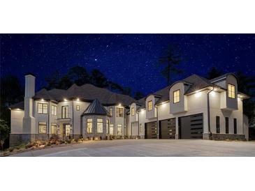 Stately two-story stucco home with a stone tower and multiple garage doors under a starry night sky at 3451 Paces Valley Nw Rd, Atlanta, GA 30327