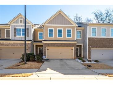 Townhome featuring a beige exterior, a brick facade, and an attached two-car garage at 813 Whittington Sw Pkwy, Marietta, GA 30060