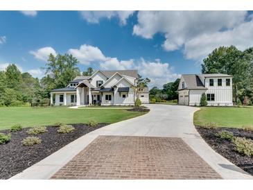 Beautiful two-story home with white siding, black trim, and professionally landscaped yard with brick paver driveway at 2497 Sugar Pike Rd, Canton, GA 30115