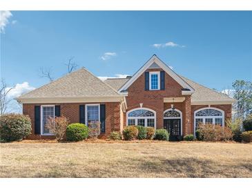 Beautiful brick home featuring a manicured lawn, complemented by lush landscaping and symmetrical design at 3999 Treemont Ln, Suwanee, GA 30024