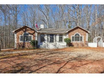 Charming stone-accented home with a welcoming front yard and a quaint white picket fence and arbor at 332 Stonecutters Cv, Stockbridge, GA 30281