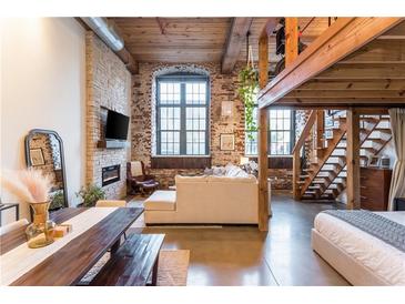 Spacious living room with exposed brick, fireplace, large windows, and a loft at 170 Boulevard Se # 111H, Atlanta, GA 30312