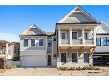 Charming two-story home with a covered porch, attached garage, brick driveway, and manicured landscaping at 320 Gray Shingle Ln, Woodstock, GA 30189