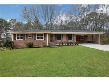 Charming brick ranch-style home featuring a well-manicured lawn, covered carport, and mature trees at 4169 Cedar Valley Ln, Conley, GA 30288