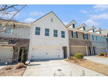 Beautiful townhouse with a two-car garage and white brick facade under a clear blue sky at 2978 Edgemont Ln, Marietta, GA 30008