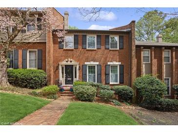 Charming brick townhouse with black shutters, manicured lawn, and blooming tree at 5273 Glenridge Dr # 5273, Sandy Springs, GA 30342