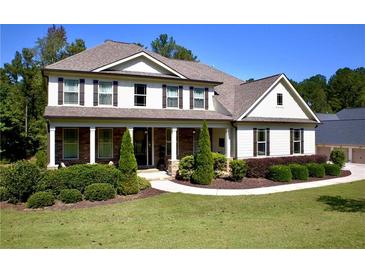 Beautiful two-story home featuring a manicured lawn and inviting covered porch with stone accents at 140 Discovery Lake Dr, Fayetteville, GA 30215