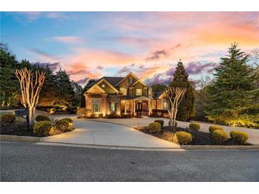 Beautiful exterior view of the home with a circular driveway and professional landscaping, complemented by a colorful sunset at 2805 Cambria Ct, Cumming, GA 30041