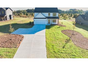 New construction home featuring a manicured lawn, concrete driveway, and a two-car garage at 3563 New Hope Rd, Dacula, GA 30019