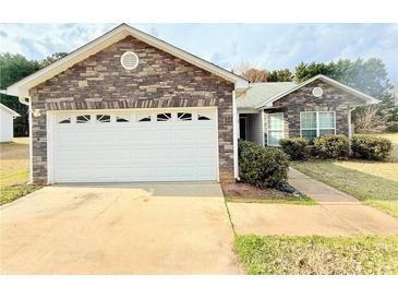 Charming single-story home featuring a stone facade and a spacious two-car garage at 125 Whistle Way, Locust Grove, GA 30248