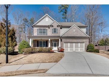 Charming two-story home with a three-car garage, manicured lawn, and inviting front porch at 5242 Park Vale Dr, Sugar Hill, GA 30518