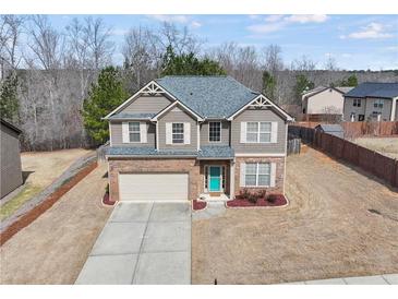 Charming two-story home featuring a brick facade, teal front door, and well-maintained front lawn at 520 Ballyshannon Dr, Dacula, GA 30019