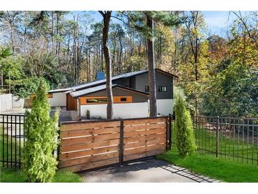 Stylish modern home exterior featuring a wooden fence, unique architecture, and lush green surroundings at 2751 Margaret Mitchell Nw Dr, Atlanta, GA 30327