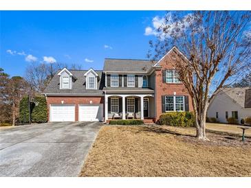 Charming two-story brick home featuring a three-car garage, well-manicured lawn, and inviting front porch at 935 Sunset Ridge Ln, Lawrenceville, GA 30045