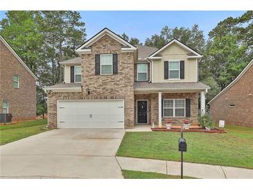 Charming two-story home with brick and tan siding, front lawn, and two-car garage at 212 Long Dr, Mcdonough, GA 30253