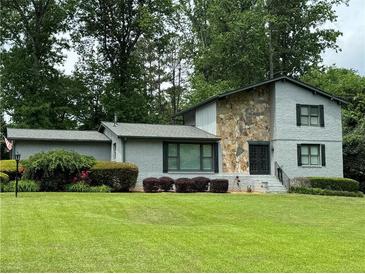 Charming two-story home featuring stone facade, manicured lawn, and lush landscaping at 4036 Winding Valley Se Dr, Smyrna, GA 30082