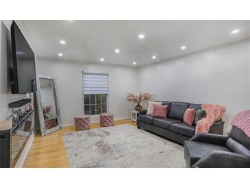 Bright living room featuring recessed lighting, hardwood floors, and a stylish gray sofa with pink accents at 5600 Kingsport Dr, Atlanta, GA 30342