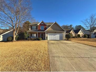 Two-story home with brick and siding exterior, well-manicured lawn, and a two-car garage with a long driveway at 2585 Kirkstone Dr, Buford, GA 30519