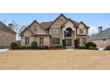 Elegant brick home with a manicured lawn, arched entryway, and lush landscaping at 3023 Lawson Dr, Marietta, GA 30064