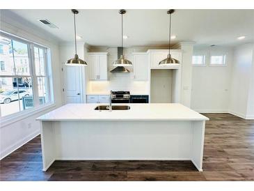 Bright kitchen features a large island with a sink, white cabinetry, stainless steel appliances, and modern pendant lighting at 3187 Moor View Rd # 37, Duluth, GA 30096