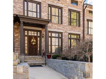 Charming brick home featuring a welcoming front entrance with a beautiful wooden door and stone walkway at 1605 Ridenour Nw Pkwy, Kennesaw, GA 30152
