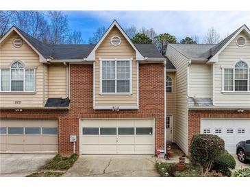 Two-story townhome with a brick facade and attached one-car garage with light-colored driveway and landscaping at 875 Edgewater Cir, Marietta, GA 30062