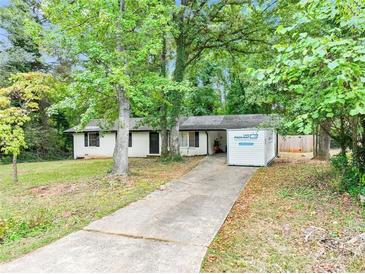 Cozy single-story home with white paint, black trim, and mature trees in a lush yard at 5626 Noblett Sw Rd, Stone Mountain, GA 30087