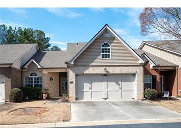 Charming townhome with a two-car garage, tan brick facade, and well-maintained landscaping at 3832 Abbott Ln # 1, Powder Springs, GA 30127