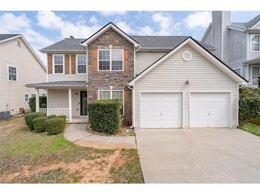 Two-story home featuring stone accents, vinyl siding, a two-car garage, and a cozy front porch at 4728 Sedum Way, Atlanta, GA 30349