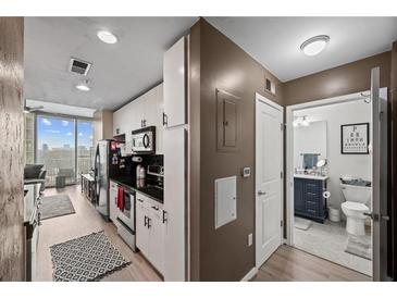 Modern kitchen featuring stainless steel appliances, white cabinets, and a stunning city view from the adjacent living area at 361 17Th Nw St # 807, Atlanta, GA 30363