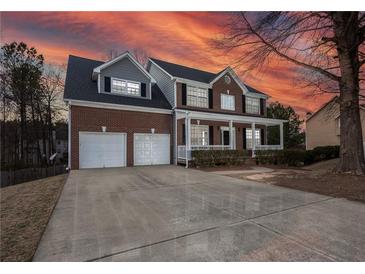 Charming two-story brick home with a welcoming front porch and two-car garage against a stunning sunset backdrop at 2124 Mitford Ct, Dacula, GA 30019