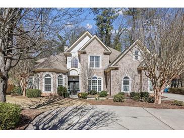 Charming brick two-story home featuring manicured landscaping, a circular driveway, and mature trees at 891 Legacy Woods Dr, Norcross, GA 30093