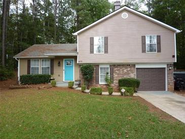 Charming two-story home with a well-manicured lawn, brick accents, and a vibrant turquoise front door at 4678 Browns Mill Ferry Rd, Lithonia, GA 30038