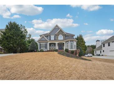 Charming two-story home featuring stone accents, a well-manicured lawn, and a welcoming front porch at 4740 Arbor Meadows Dr, Cumming, GA 30040