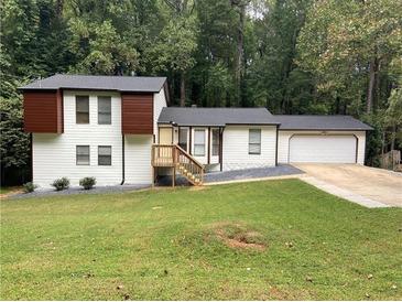 Split-level home with white siding, dark roof, attached garage and front yard at 1173 Mill Ridge Dr, Lawrenceville, GA 30045